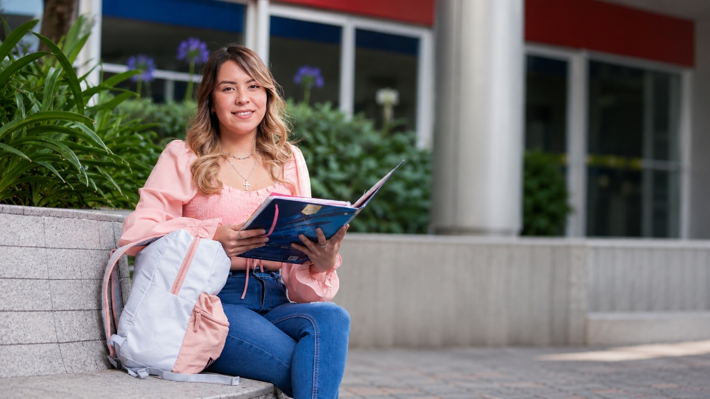 Estudiante de UniverMilenium con sus materiales de estudio en el campus.
