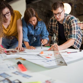 Female,Designers,Discussing,Over,Blueprint,With,Male,Designer.,One,Of